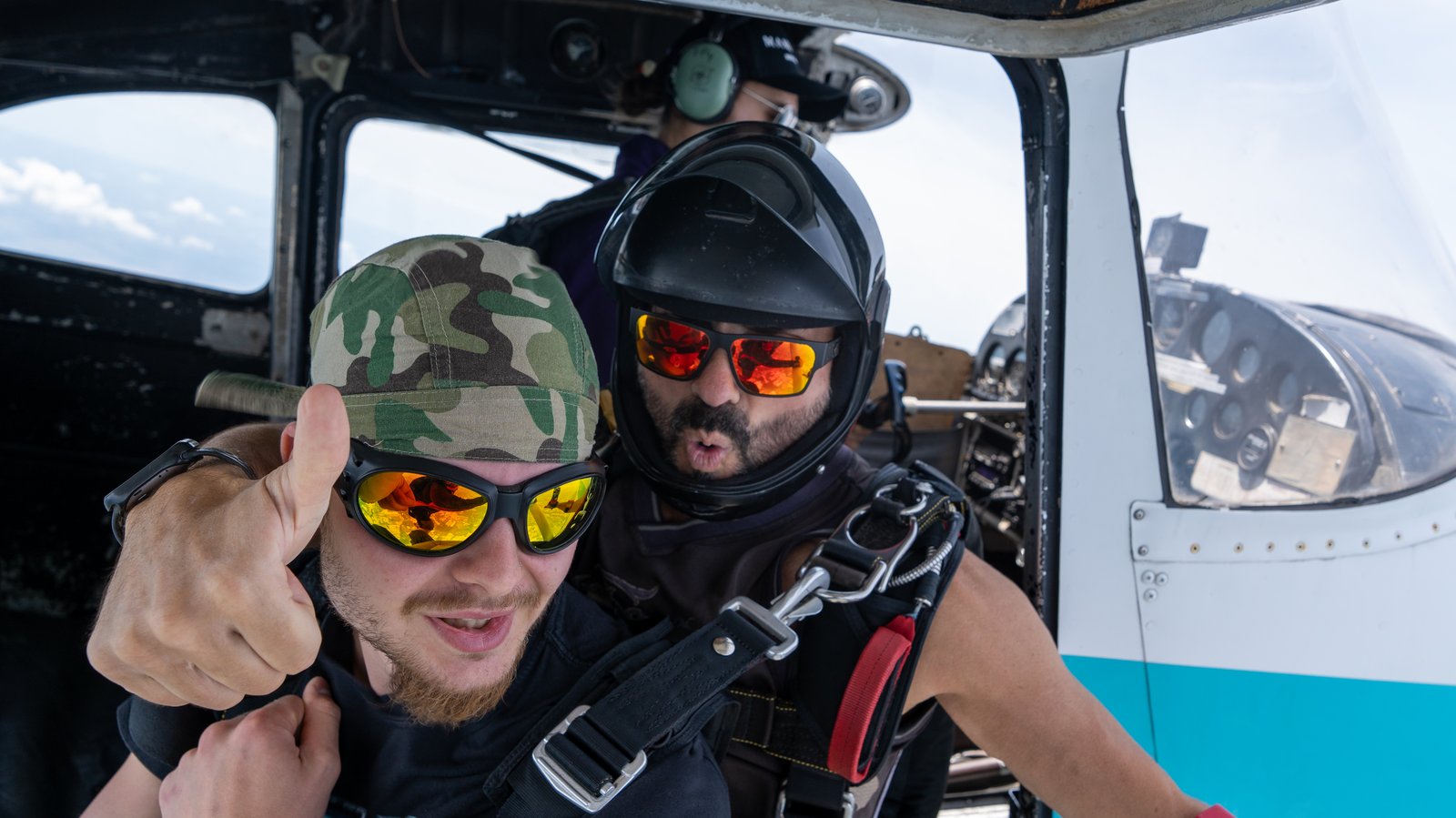 Smiling first-time tandem skydiver giving a thumbs-up before exit at Skydive SWOOP near Toronto