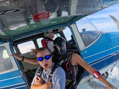 Excited tandem skydiver grinning in the aircraft door before a group jump near Toronto